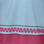 Close-up of a fabric hem with a light blue top, a pink geometric pattern band, and a solid pink bottom.