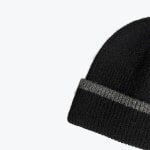 Close-up of a black ribbed knit beanie with a grey stripe on the folded brim, set against a white background.