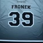 The back of a gray gradient hockey jersey with the name FRONEK and the number39 printed in black block lettering with white outlines.
