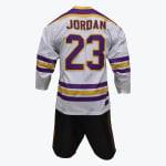 Back view of a white hockey jersey with JORDAN in purple and gold, featuring matching stripes on the sleeves and hem, paired with black shorts.