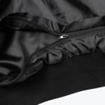 Close-up of a black jacket zipper, smooth lining, and ribbed knit hem.