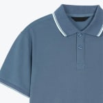 Close-up of a slate blue short-sleeve polo shirt with white stripes on the collar and cuffs.