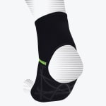 A black compression ankle sleeve with an open heel, neon green stitching, and a grey geometric pattern on the bottom, displayed on a stylized foot model.