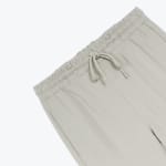 Close-up of the elastic waistband and drawstring on a pair of light beige trousers.