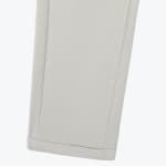 Close-up view of the hem of light gray textured trousers with clean stitched seams.
