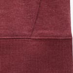 Close-up of a burgundy heathered sweatshirt showing the texture of the body fabric and the ribbed hem.