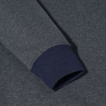 Close-up of a heathered grey sweatshirt sleeve featuring a contrasting navy blue ribbed knit cuff.