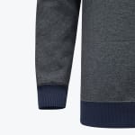 Close-up of a grey textured knit sweatshirt showing a sleeve with a navy blue ribbed cuff and the bottom hem with a matching navy blue ribbed band.