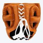 Rear view of a tan leather boxing headguard with white laces tied in a bow on a white background.