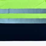 Close-up of high-visibility safety clothing with neon green fabric, two silver reflective bands, and a navy blue bottom section.