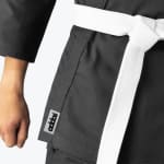 Close-up of a black martial arts uniform with a white belt tied at the waist and an Addos logo tag on the hem.