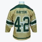 The back of a gold hockey jersey with HAYTON and the number 42 printed in green block lettering with white borders.