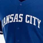 Close-up of a royal blue baseball jersey with KANSAS CITY printed in arched white block letters across the chest.