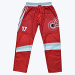 Red inline hockey pants with the number 17 on the right thigh, a winged wheel logo on the left thigh, and white and grey stripes on the legs.