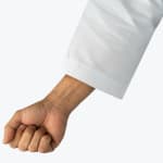 A close-up of a clenched fist and forearm in a white martial arts gi sleeve, isolated on a white background.