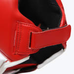 Close-up of a red leather boxing headgear showing the adjustable strap and stitching details.
