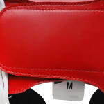 Close-up of a red leather strap with double stitching and a white size tag showing the letter M.