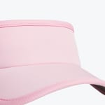 Close-up view of a light pink sun visor showing the front band and brim with detailed stitching.