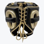 Rear view of a black and gold leather boxing headguard showing the gold lace-up closure and padded ear protectors on a white background.