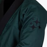 Close-up of a dark green BJJ gi sleeve featuring a textured weave and embroidered black four-pointed stars.