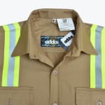 Close-up of a khaki flame-resistant work shirt with high-visibility reflective stripes and an Addos brand label.