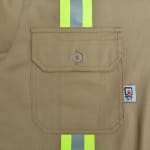 Close-up of a khaki work shirt pocket with a buttoned flap, a vertical yellow and silver reflective safety stripe, and an NFPA 2112 flame-resistant label.