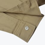 Close-up of a khaki twill shirt cuff showing a light-colored button and buttonhole.