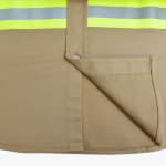 Close-up of a tan safety work shirt showing the fabric texture, button placket, bottom hem, and a yellow-and-silver reflective safety stripe.