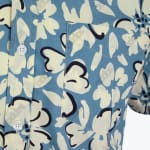 Close-up of a dusty blue and cream floral print button-down shirt with a chest pocket and white buttons.
