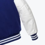 Close-up of a blue varsity jacket with a white sleeve and striped ribbed cuffs.