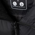 Close-up of a black jacket interior label showing size M, water resistant and isotherm warmth icons, and a partially open zipper.