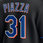 The back of a black baseball jersey showing the name PIAZZA and the number 31 in blue with white and orange borders.