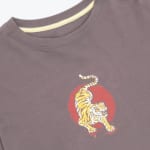 Close-up of a dark brown crew neck t-shirt with a graphic of a yellow tiger on a distressed red circle.