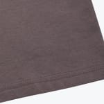 Close-up of a brown knit fabric hem with double-needle stitching against a white background.