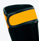 Close-up of a bright orange leather wrist strap on a black boxing glove with detailed stitching.