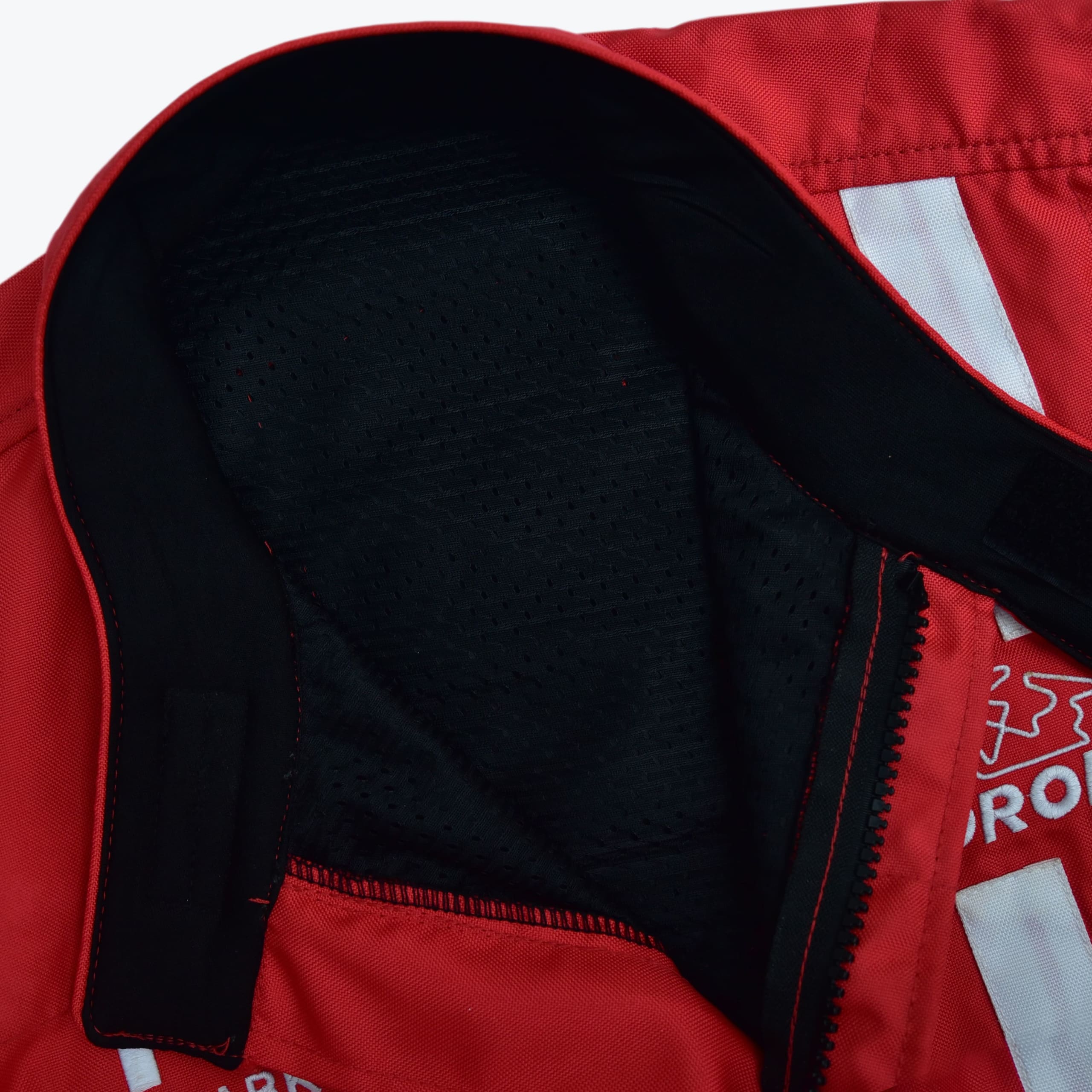 Close-up of a red jacket collar showing the black mesh inner lining and black fabric trim with Velcro fasteners.