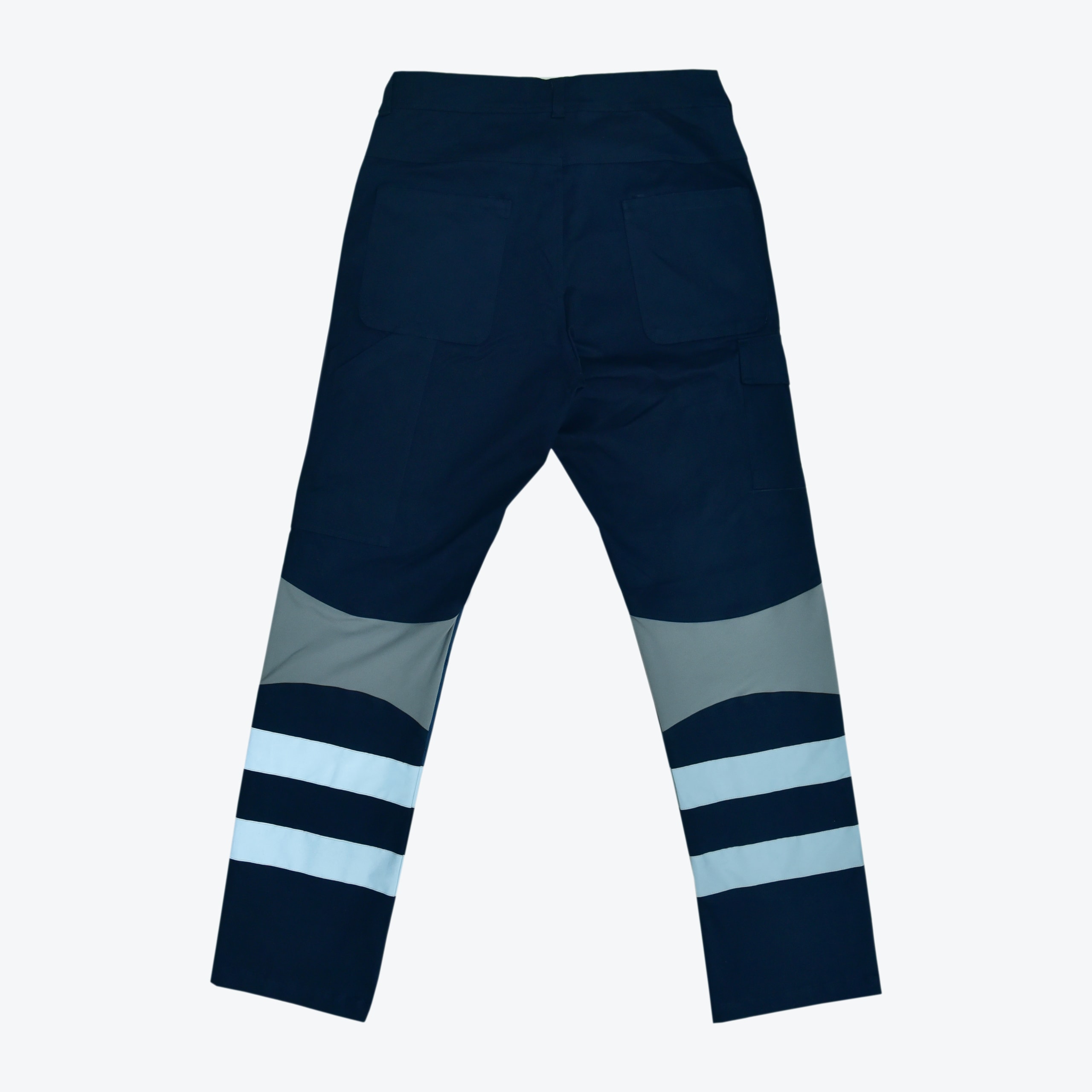 Back view of navy blue high-visibility work pants with grey knee patches and double reflective silver stripes on the lower legs.