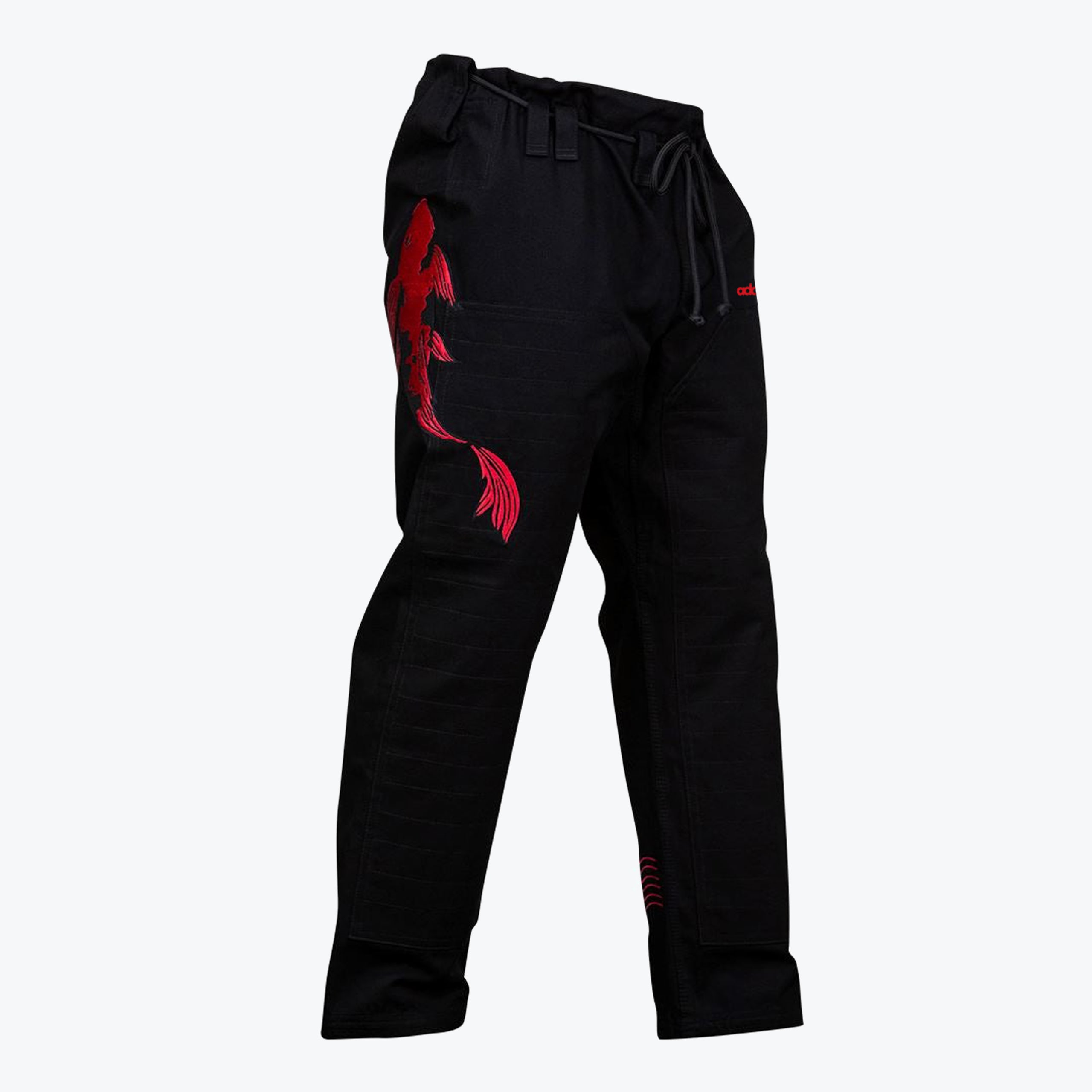 A pair of black martial arts gi pants with a large red embroidered koi fish on the right thigh, set against a solid white background.