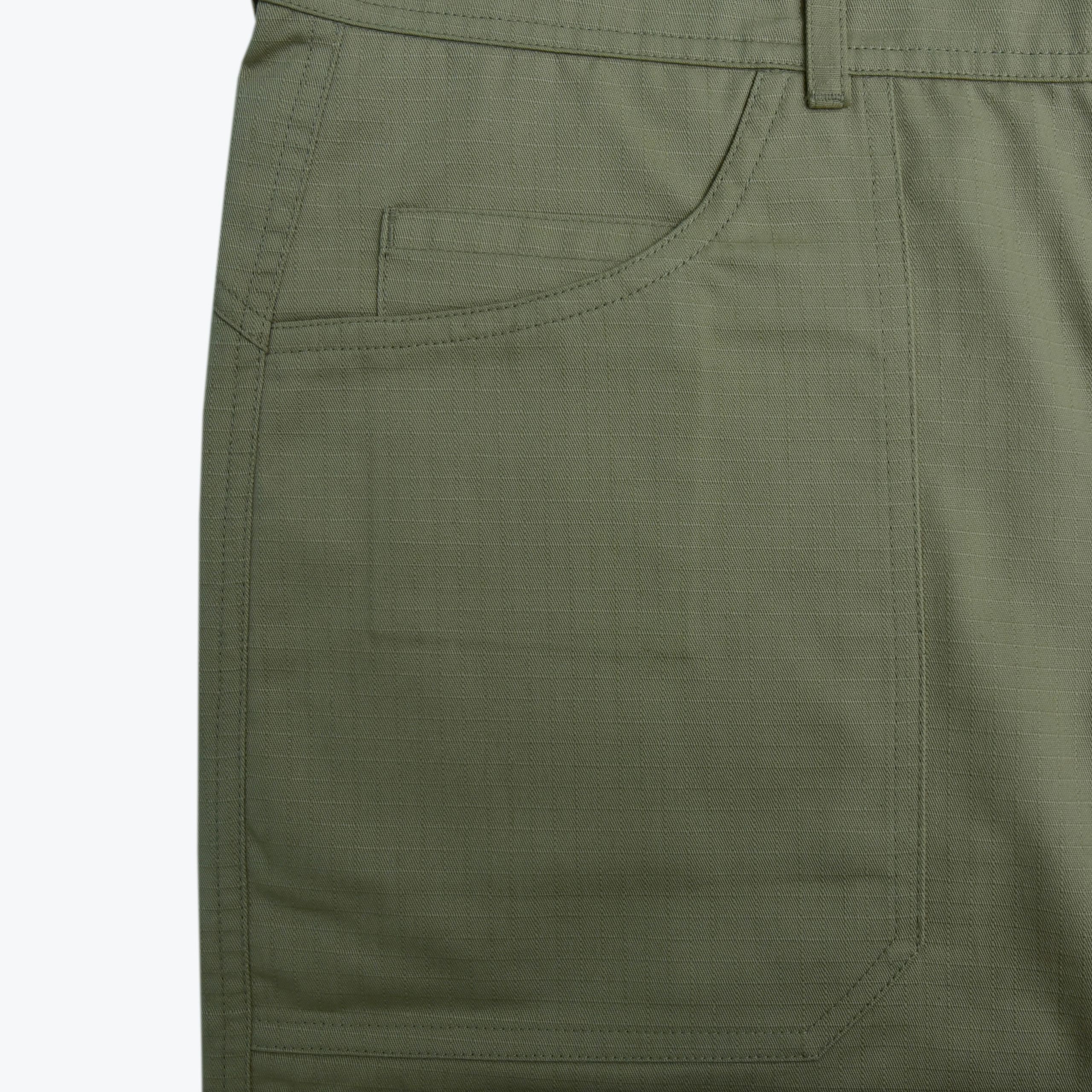 Close-up of a front patch pocket on olive green pants with a smaller coin pocket inside.