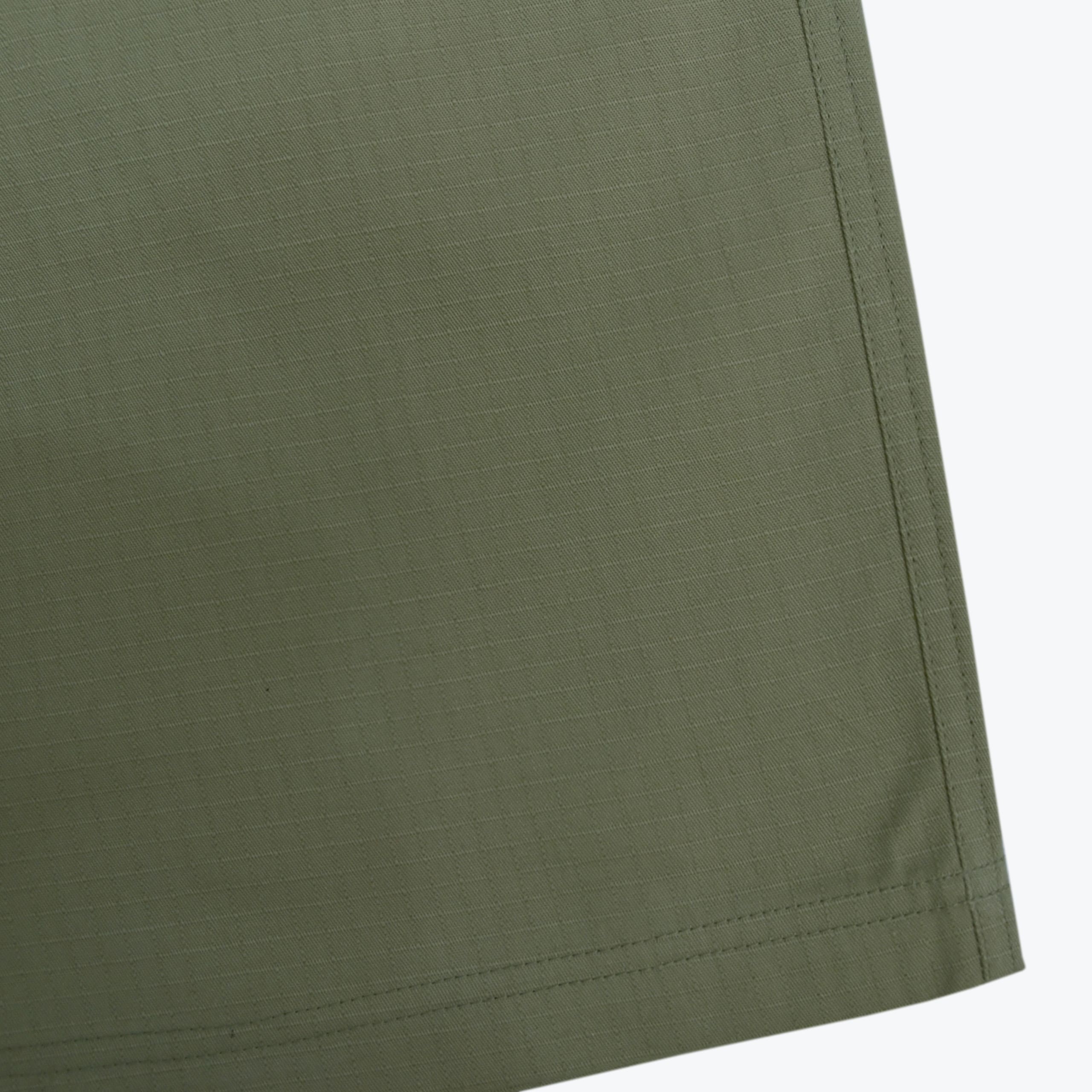 Close-up of olive green ripstop fabric with a double-stitched hem and side seam.
