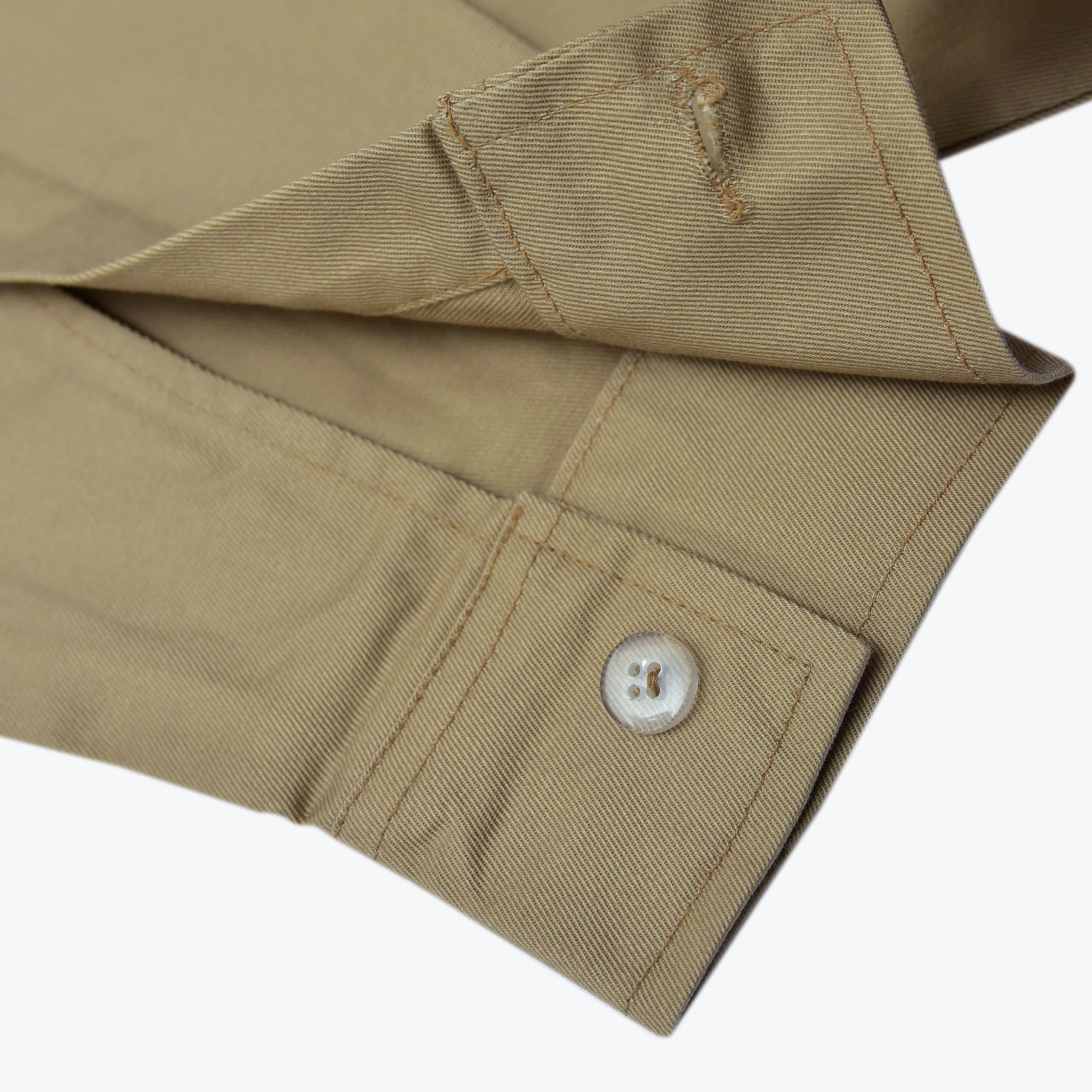 Close-up of a khaki twill shirt cuff showing a light-colored button and buttonhole.