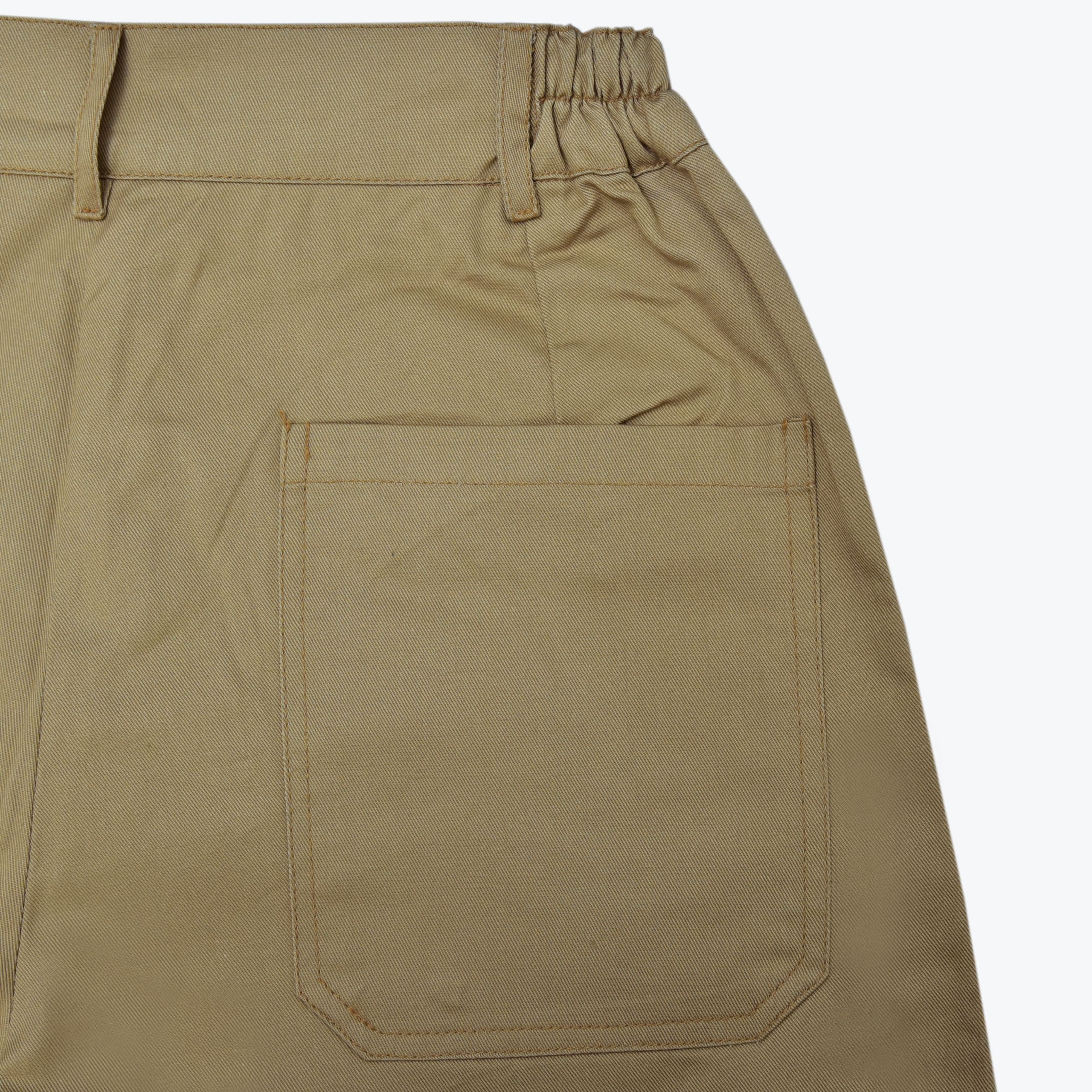 Close-up of a large patch pocket on the back of beige khaki pants, showing the waistband and belt loops.