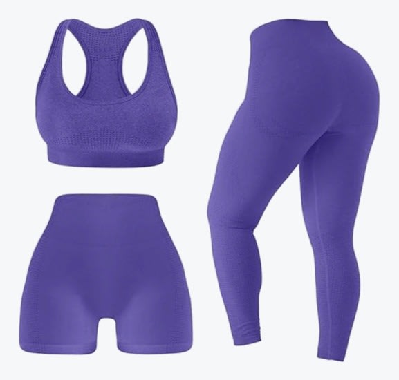 A three-piece purple seamless workout set featuring a sports bra, high-waisted shorts, and high-waisted leggings on a plain white background.