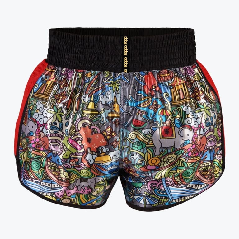A pair of colorful Muay Thai shorts with a detailed Thai-themed cartoon print, a thick black waistband, and red mesh sides, displayed against a white background.