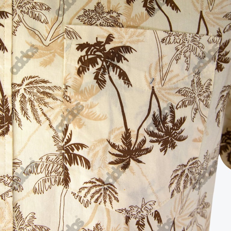Close-up of a cream-colored shirt with a brown and beige palm tree pattern and a matching front pocket.