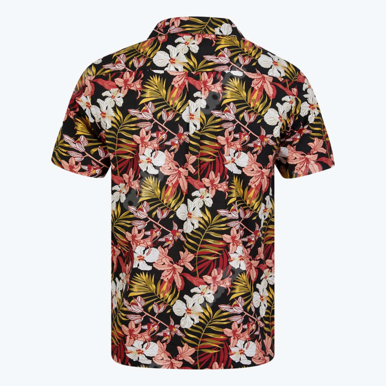 The back of a short-sleeved black Hawaiian shirt covered in a dense pattern of white hibiscus flowers, pink lilies, and yellow-green palm fronds.