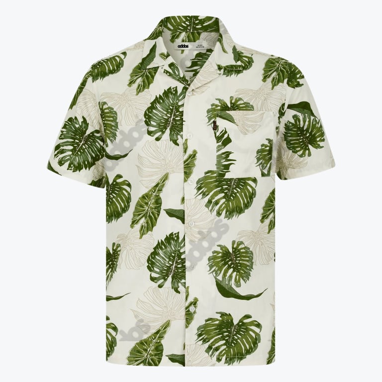 A white short-sleeved button-up shirt with a green monstera leaf pattern, featuring a camp collar and a left chest pocket.