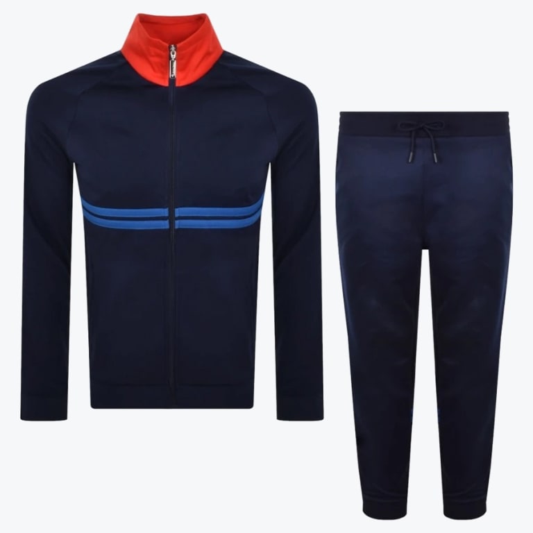 A navy blue tracksuit set consisting of a zip-up jacket with a red collar and blue chest stripes, and matching navy blue pants with a drawstring waist, displayed against a white background.