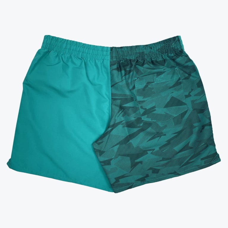 A pair of split-design swim shorts, with one half solid teal and the other half covered in a teal and dark green geometric pattern.