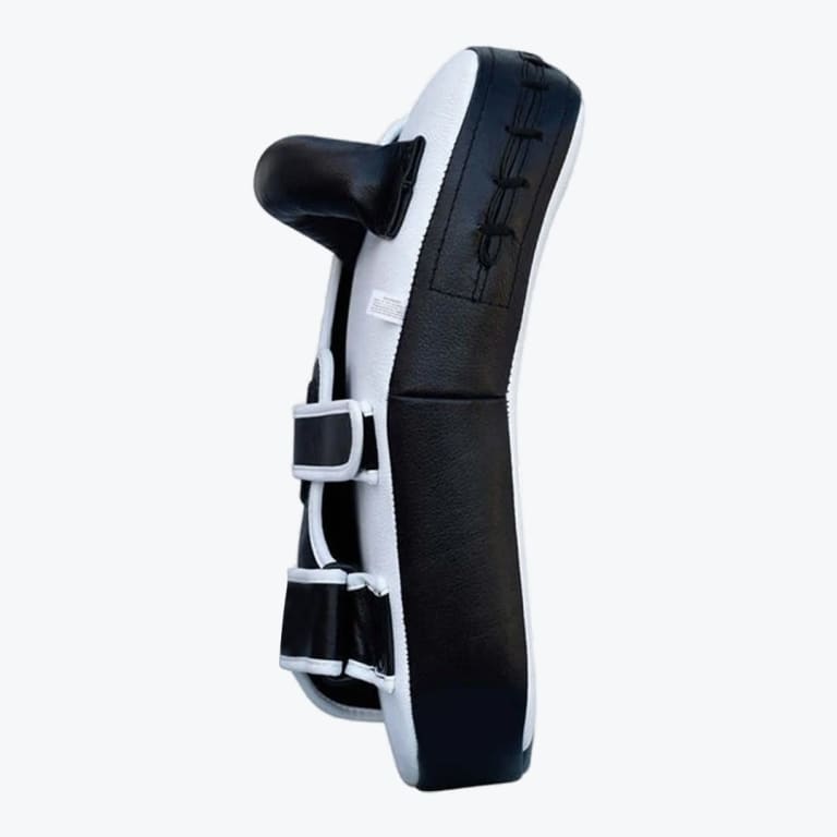 Side view of a black and white curved Muay Thai kick pad with a handle and two adjustable arm straps on a plain white background.
